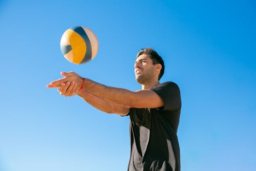 An adult male playing volleyball outdoors against a clear blue sky. Perfect for sports and lifestyle themes.