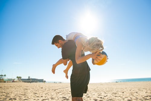 Mann Im Schwarzen T Shirt Und In Den Grünen Shorts, Die Basketball Am Strand Halten