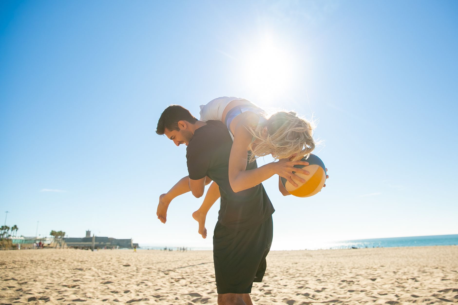 A carefree couple playing with a volleyball on a sunny beach, exuding joy and youthfulness.