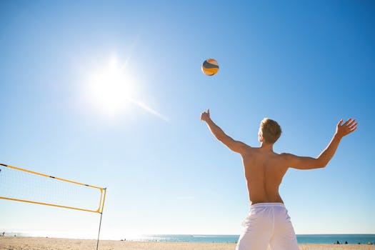 Shirtless man serving a volleyball on a sunny beach, perfect for fitness and sports themes.