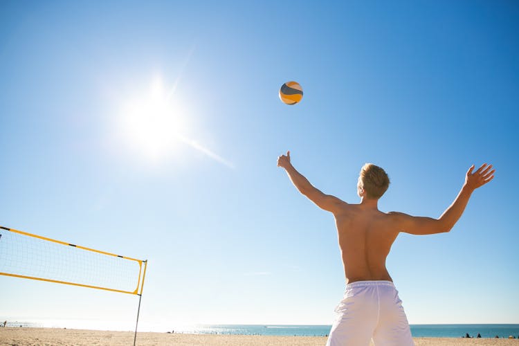 A Man Playing Volleyball On The Beach