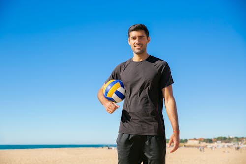Homme En T Shirt à Col Rond Noir Tenant Un Ballon De Volleyball Jaune