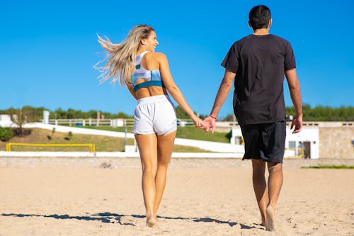 黑色t恤的男人和藍色比基尼的女人在海灘上散步
