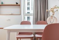 White dining table with chairs in interior of contemporary room with shelves and window with curtains