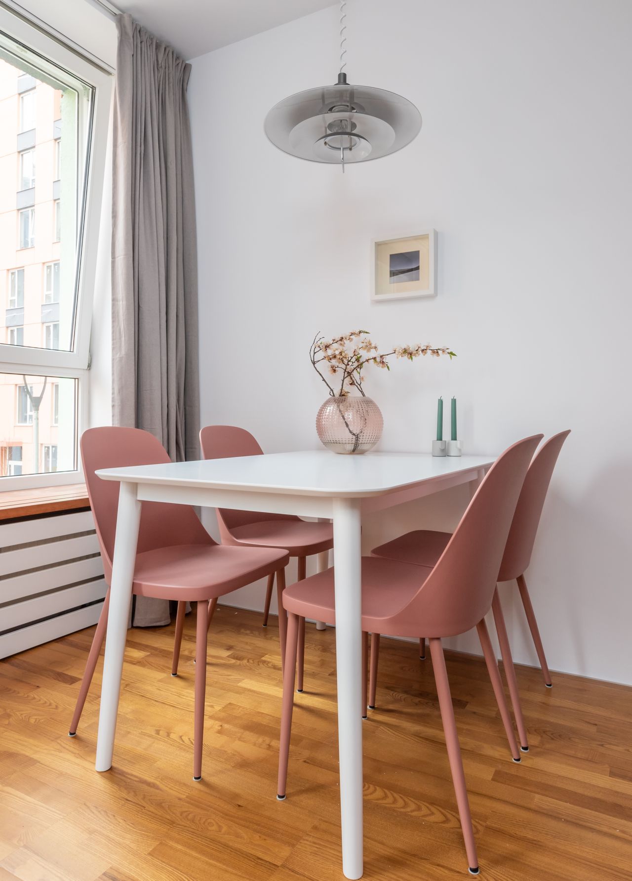 Small white dining table with pink chairs in a bright nook