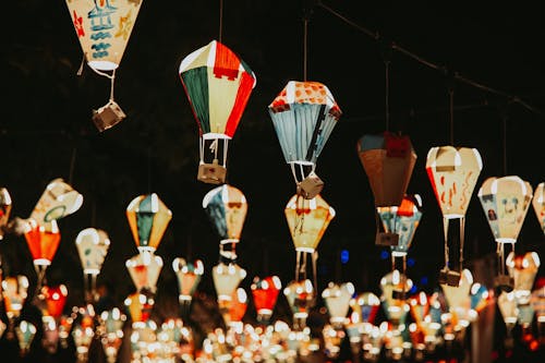 Abundance of traditional multicolored glowing lanterns painted in oriental style hanging on street in night time on blurred background during