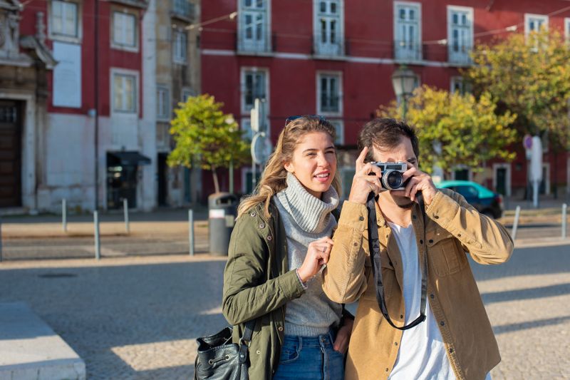 Couple capturing street photos in an urban setting, embracing travel vibes.