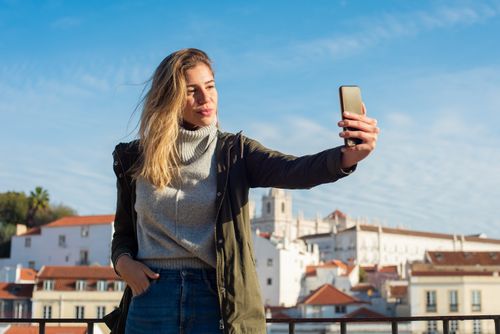 Free Young woman taking a selfie outdoors in a picturesque European city setting. Stock Photo