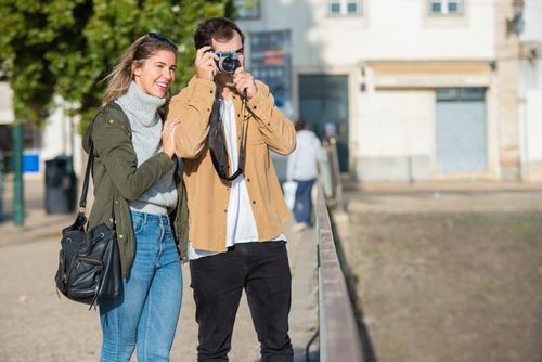 Free Couple enjoying a sunny day, capturing memories with a camera in a city street. Stock Photo