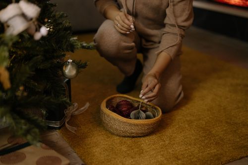 Free Person decorating a Christmas tree with ornaments, creating a cozy holiday atmosphere. Stock Photo