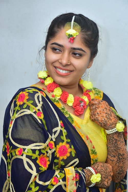 Free Smiling Indian woman wearing traditional attire with intricate henna and floral jewelry. Stock Photo