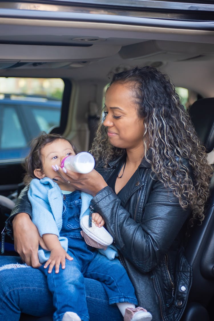 

A Woman Feeding Her Child With A Bottle Of Milk