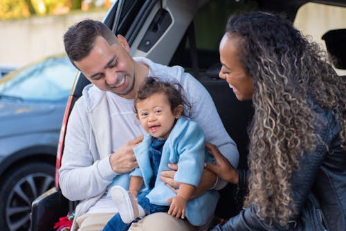 Free Man in Blue Hoodie Carrying Baby in Blue Long Sleeve Shirt Beside a Woman Stock Photo