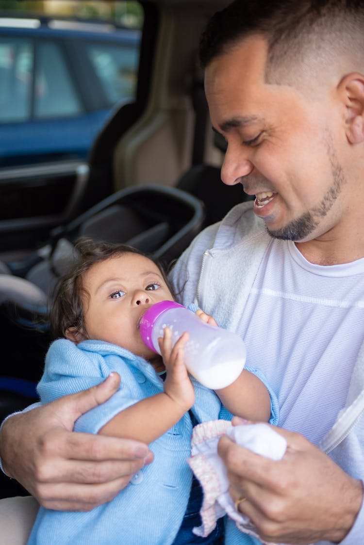 
A Man Feeding His Child With A Bottle Of Milk