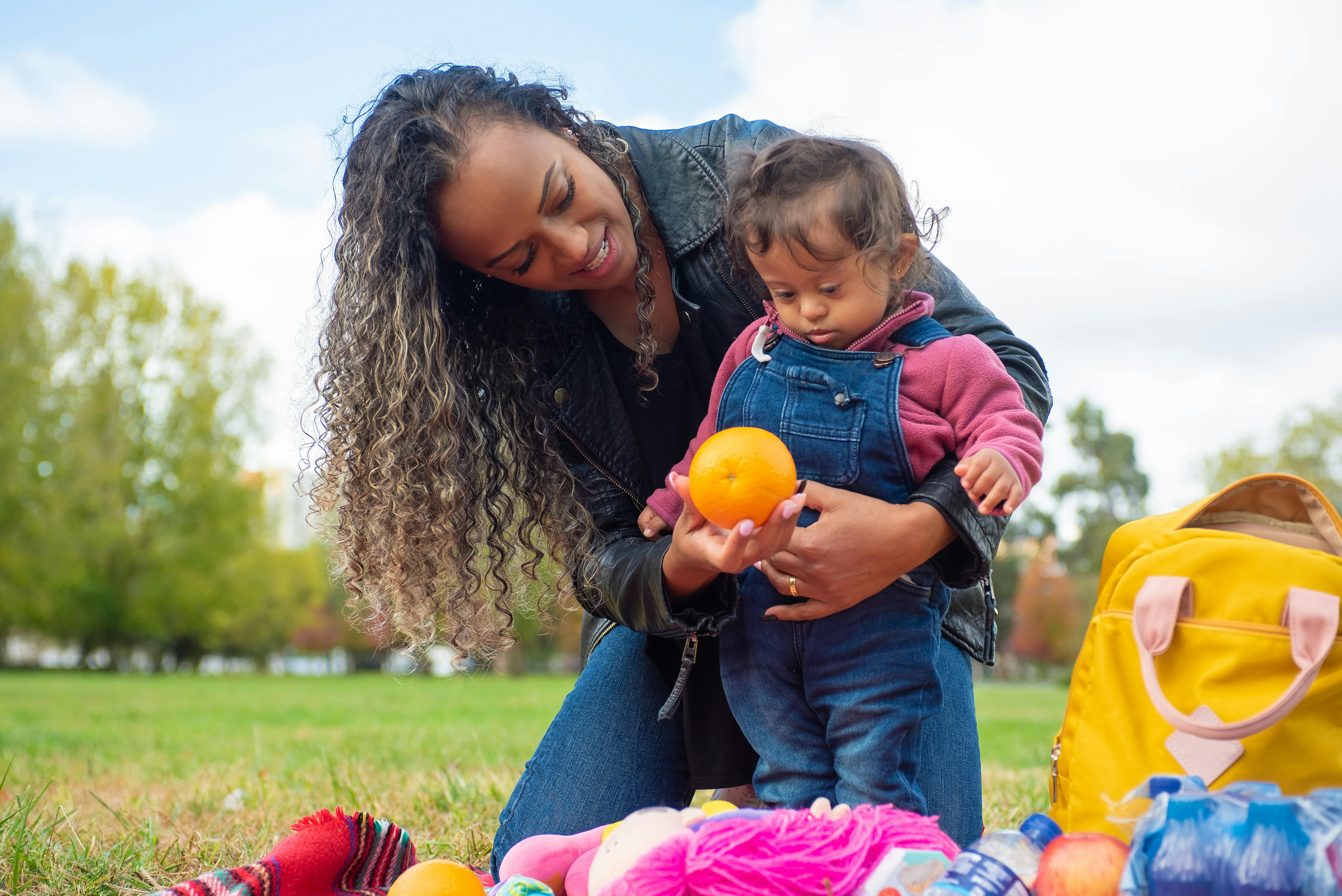 a woman showing an orange to her child