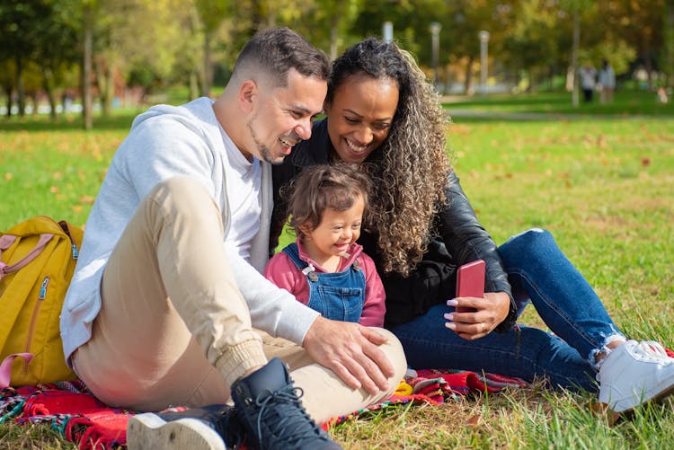 A Family Sitting On Green Grass