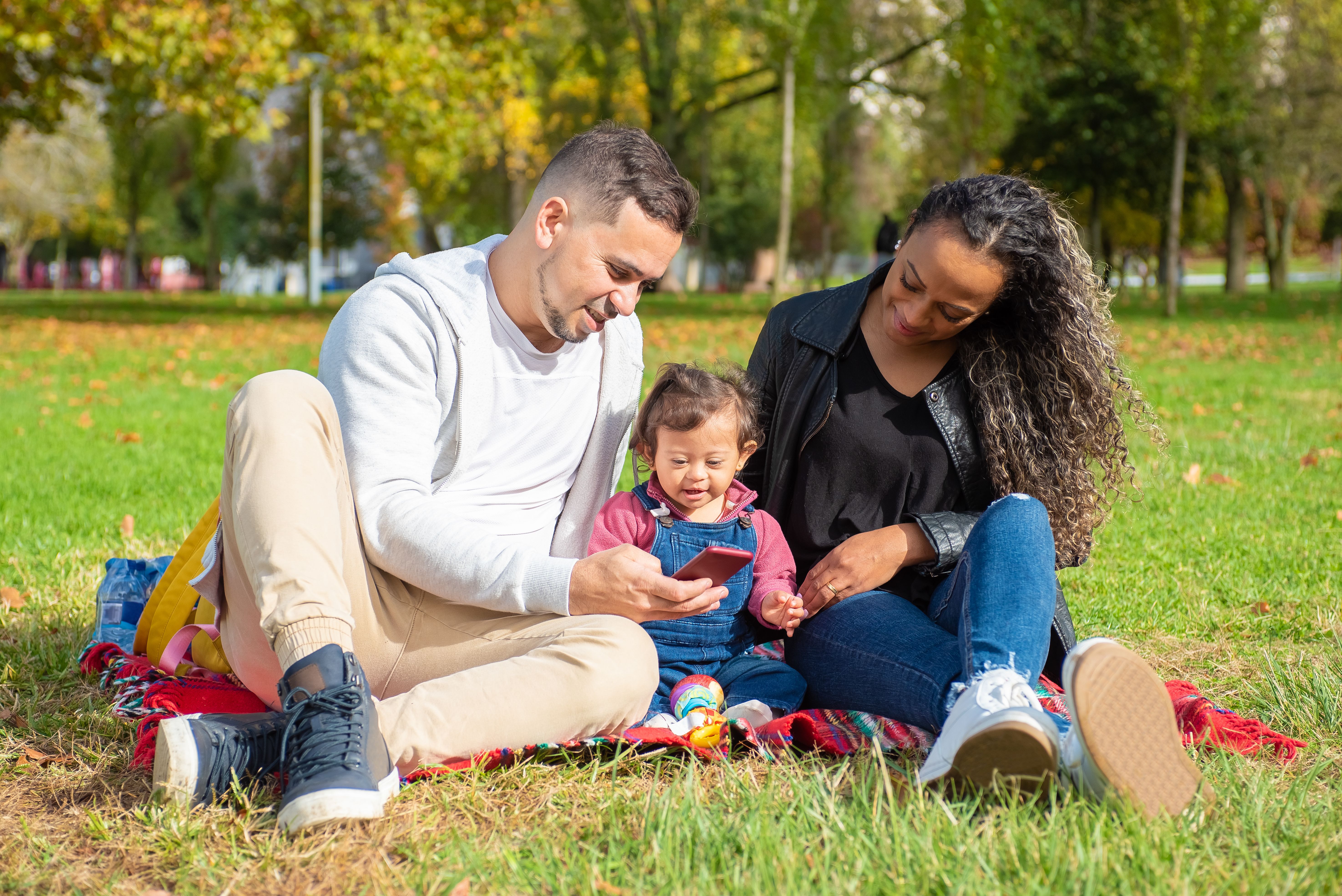 Family spending time outdoors in the park enjoying technology together.