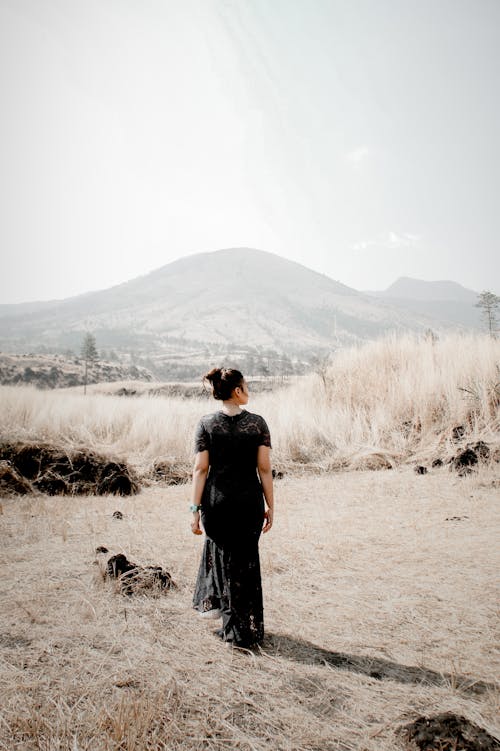 Free A Woman in a Black Dress Walking on a Field Stock Photo