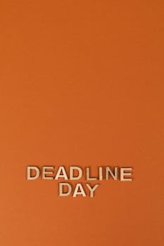 Wooden letters spelling 'Deadline Day' on an orange background, ideal for business, planning, and organization themes.