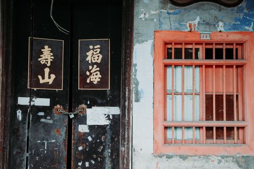 Free Old shabby door with written hieroglyphs and red window with metal grid on wall of aged building on street in city Stock Photo