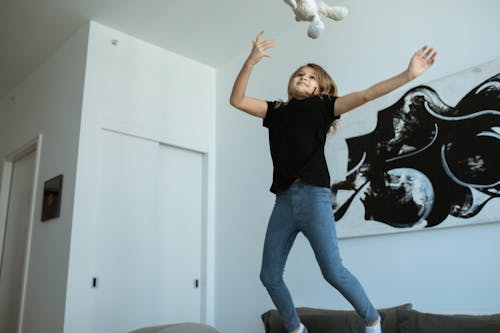 
A Girl Wearing a Black Shirt and Denim Pants Jumping