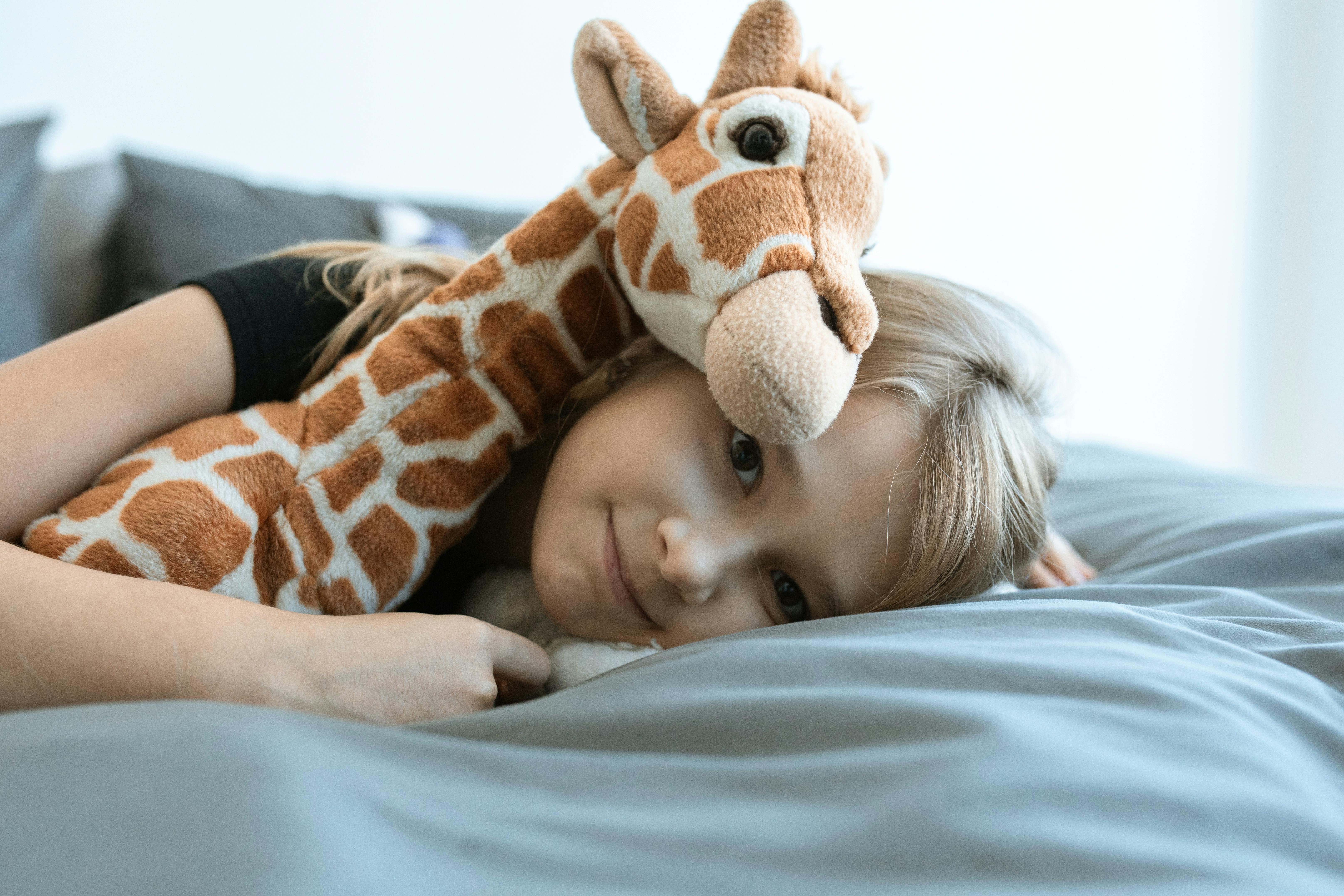 girl hugging brown and white giraffe plush toy