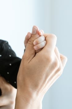 Close-up of a mother and baby's hands, symbolizing love and bond.