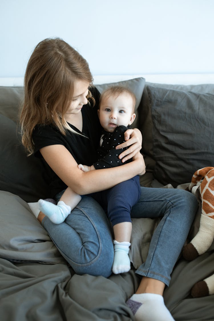 Woman In Black Shirt Sitting On Couch With A Baby