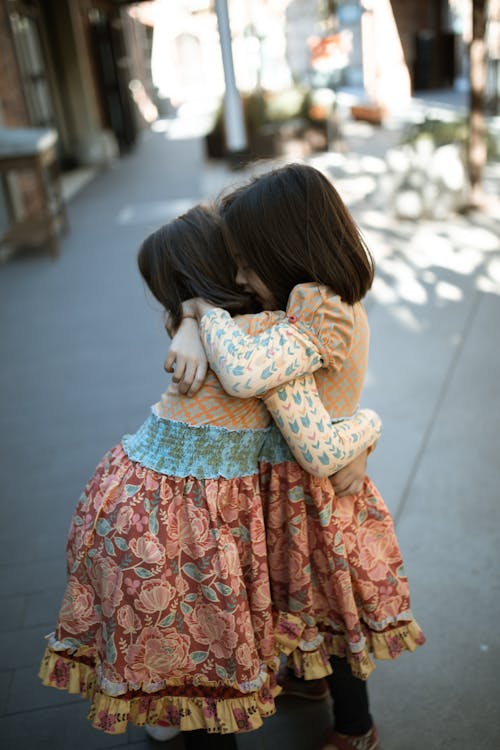 Free Girls in Orange Dresses Hugging Each Other Stock Photo