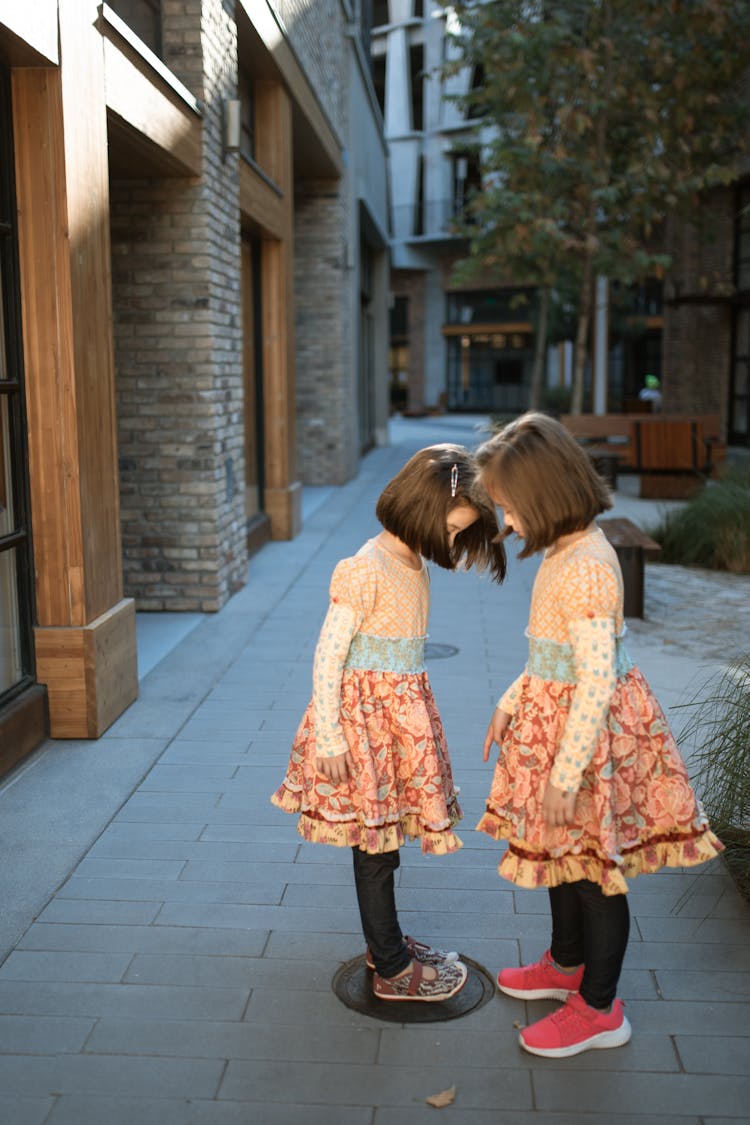 Kids In Orange Dress Standing While Facing Each Other