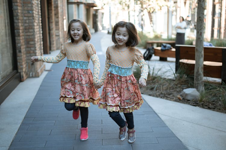 Two Girls Running On The Sidewalk