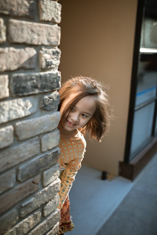 Free Little Girl Hiding Behind Brick Wall Stock Photo