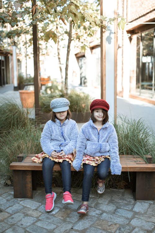 Free Two Girls Sitting on Brown Wooden Bench Stock Photo