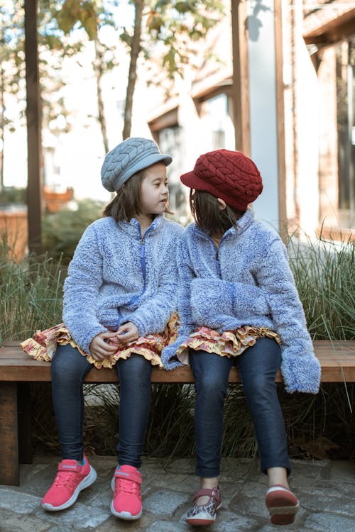 Free Girls Sitting on Brown Wooden Bench Wearing Knit Caps Stock Photo