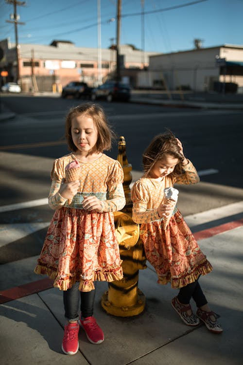 Free Two Girls Standing Beside the Fire Hydrant on Sidewalk Stock Photo