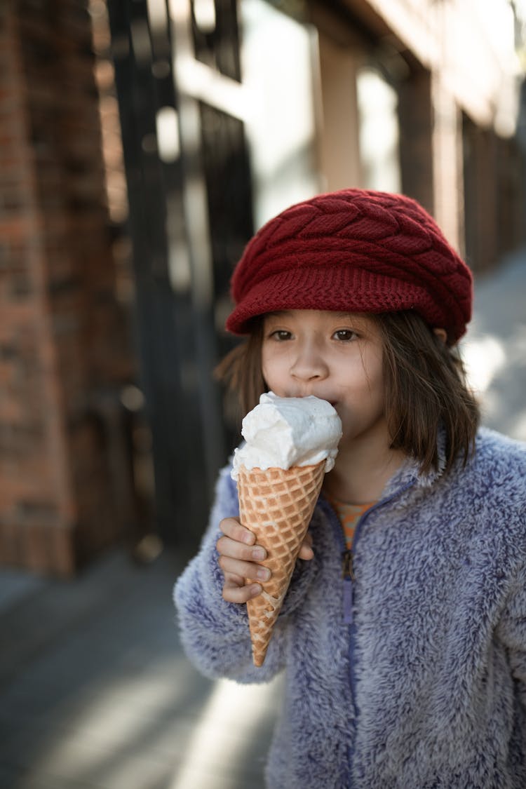 Girl In Blue Coat Eating Ice Cream Cone