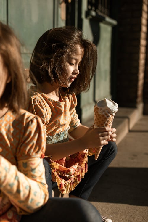 женщина в коричнево белом цветочном платье держит рожок мороженого