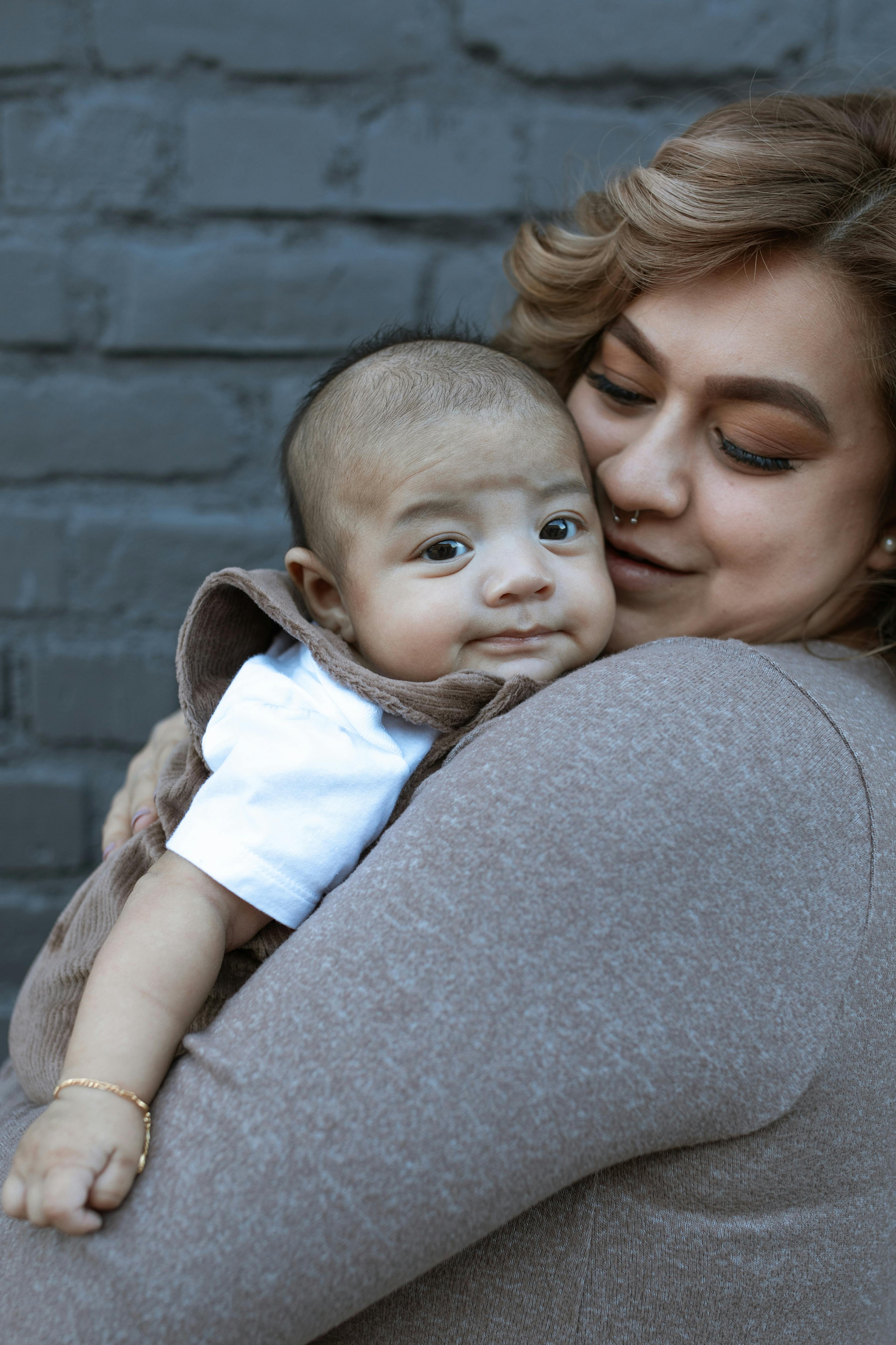 woman in gray shirt carrying baby in white shirt