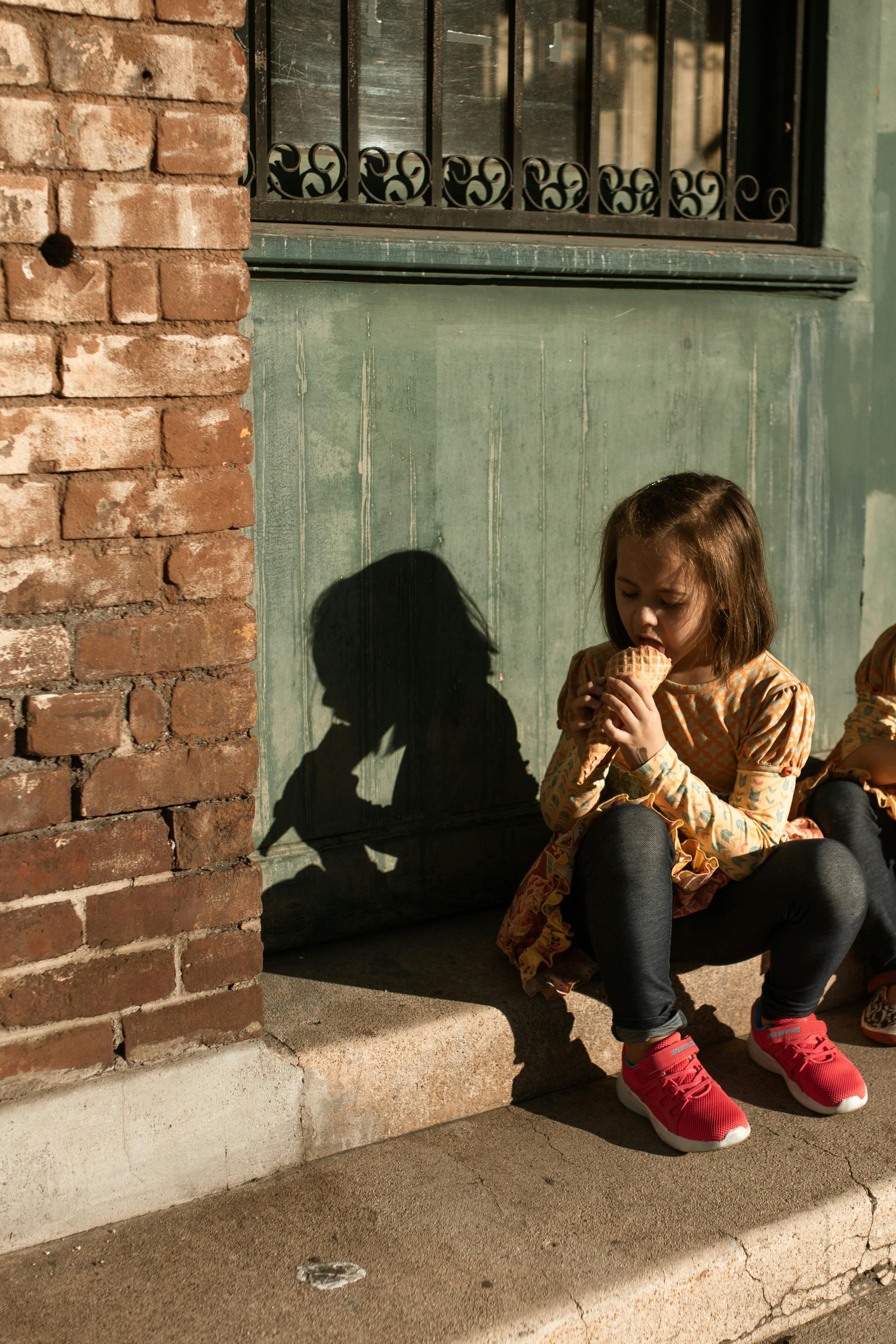 girl sitting on concrete steps eating ice cream cone