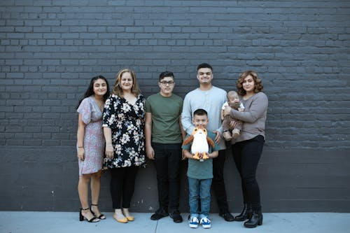 Group of People Standing Beside Gray Brick Wall