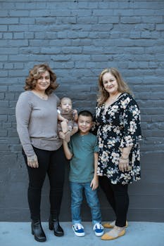 A smiling family of four including two women, a baby, and a child posing outdoors.