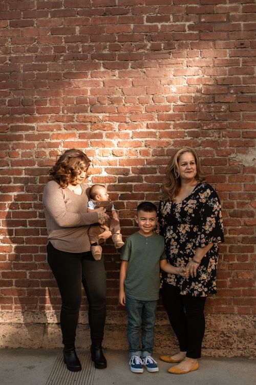 Free Family photo against a brick wall with diverse age group posing in natural light. Stock Photo
