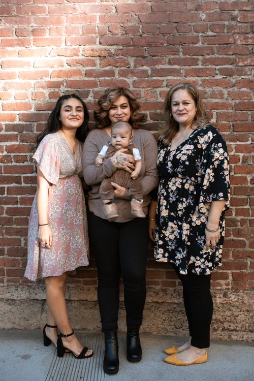 Free Three women and a baby pose together in front of a brick wall. Stock Photo