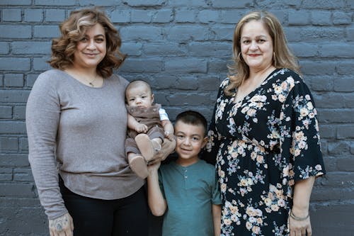 Two Women with a Boy and a Bay Standing Beside the Gray Wall