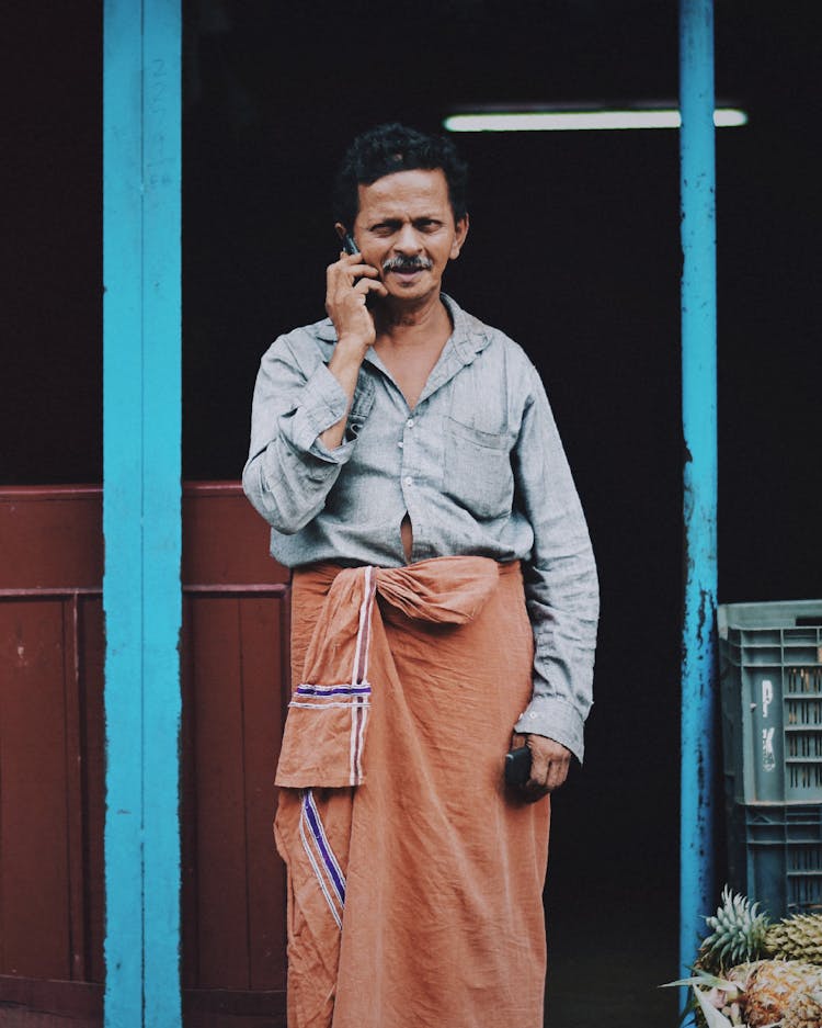 Man In Traditional Indian Clothing Talking On The Phone In The Street