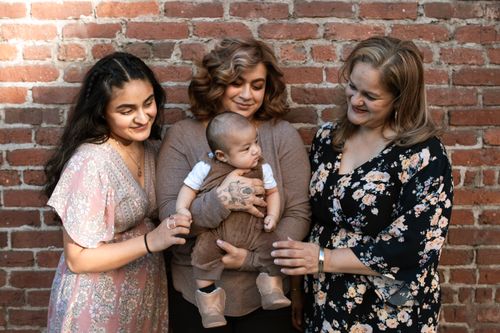 Free A loving family sharing a moment with their baby outdoors against a brick wall. Stock Photo