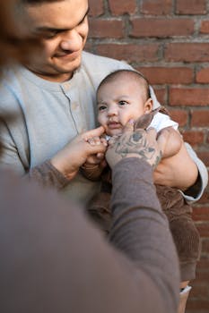 A loving moment between father and baby against a rustic brick background.