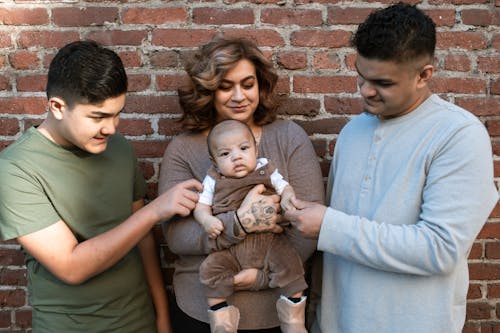 A Woman Carrying Her Baby Boy while Standing Between the Father and His Son