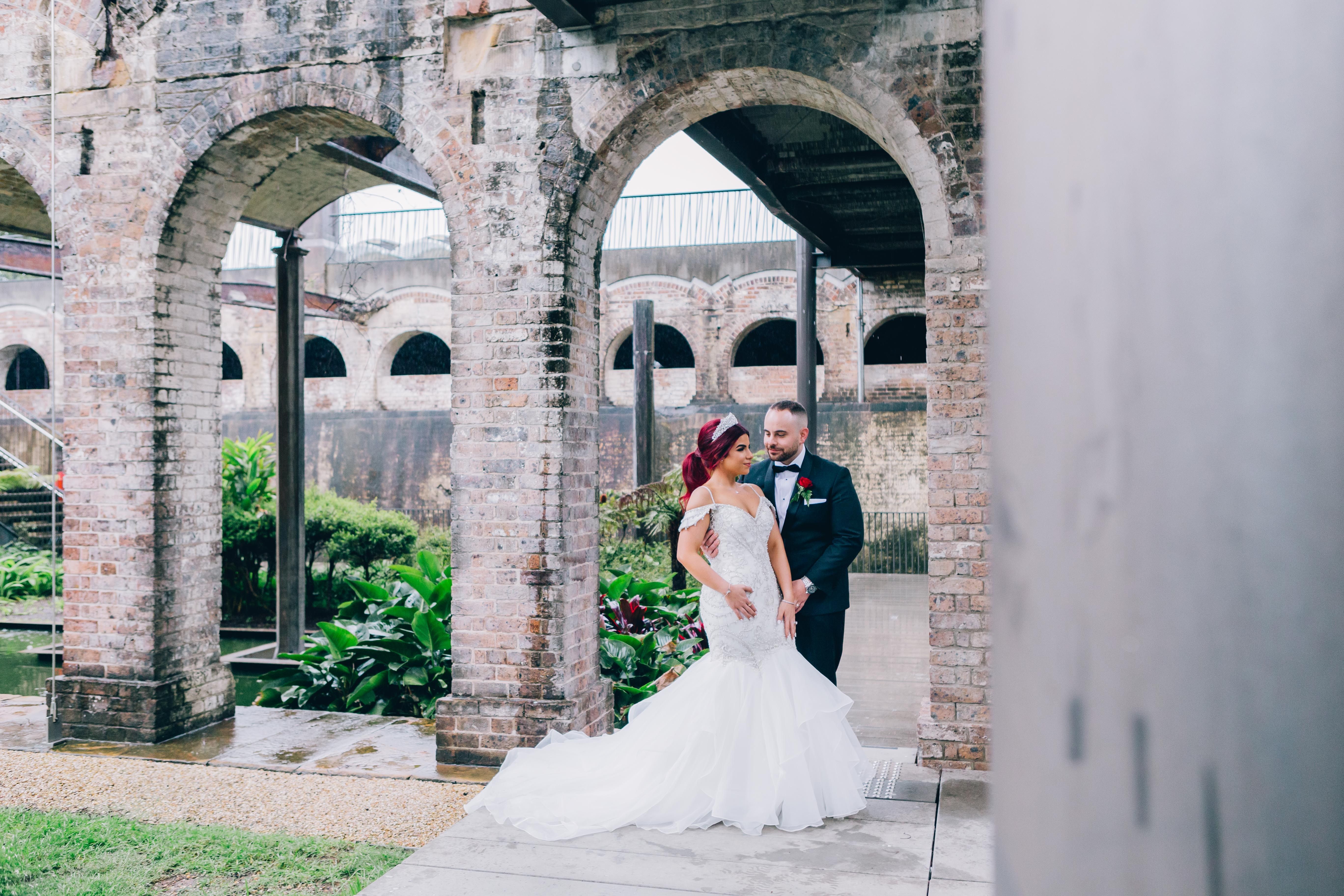 Beautiful bride and groom pose under historic arches in Paddington, NSW, Australia.