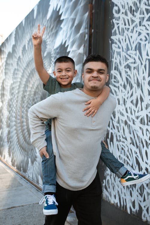 A Boy Piggy Back Riding on a Man in Gray Sweater 